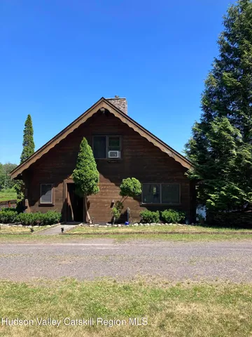a front view of house with yard and trees in the background