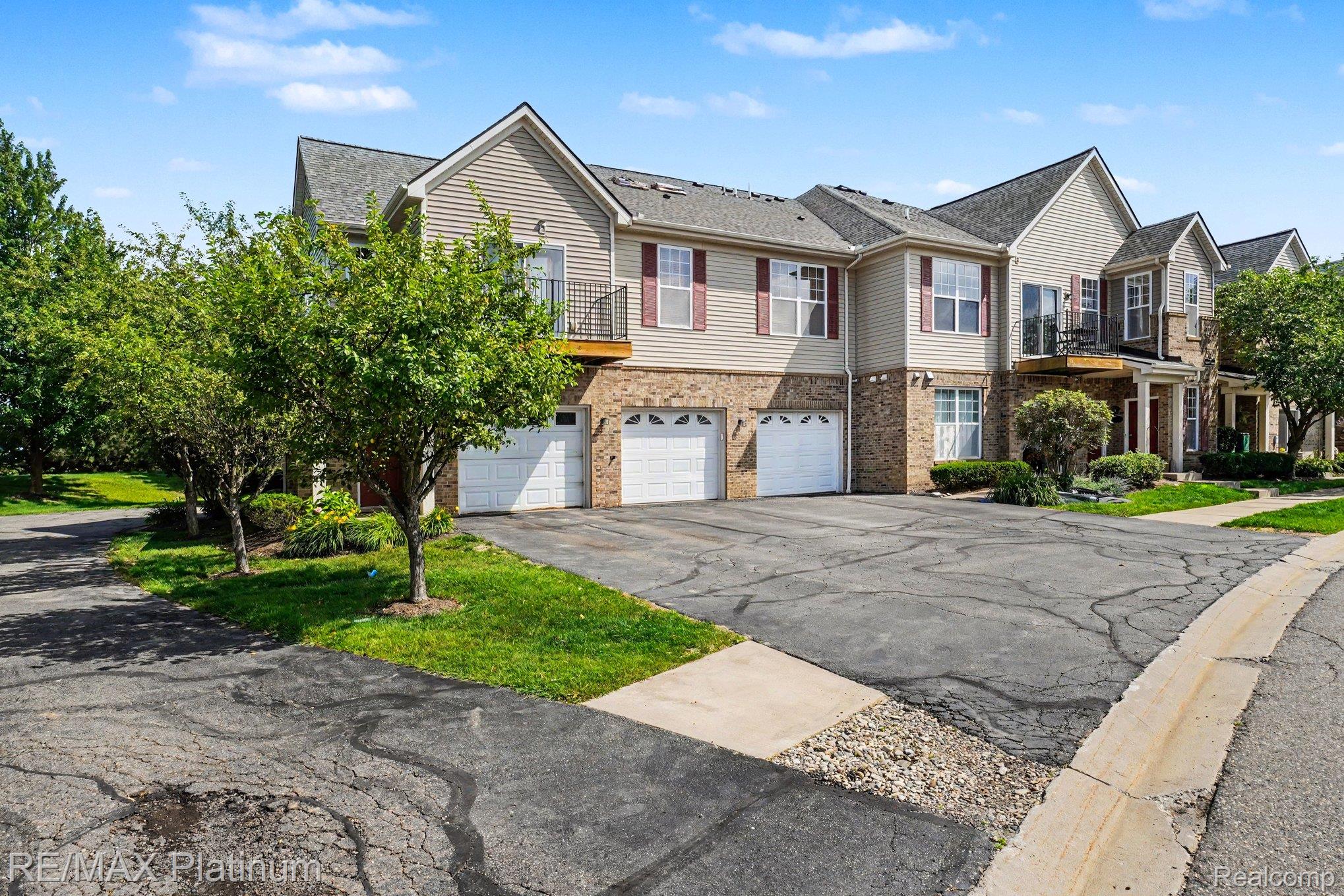 10217 Crossview Trail Howell, MI 48855 - Photo 25 of 26 Multi-level townhome featuring a neutral-toned facade with stone accents, attached garages, and private balconies