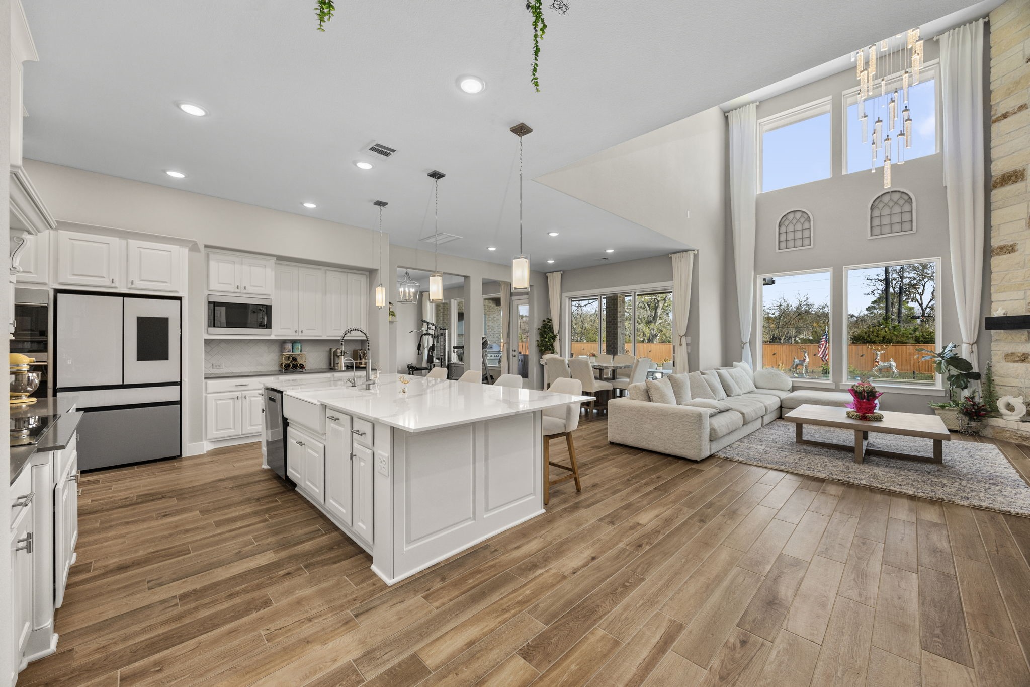 29402 Cir S Rnch Trail Fulshear, TX 77406 - Photo 13 of 50 a large white open kitchen with stainless steel appliances kitchen island a large counter top a couch and chandelier