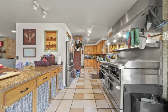 a kitchen with stainless steel appliances kitchen island granite countertop a stove a sink and a refrigerator