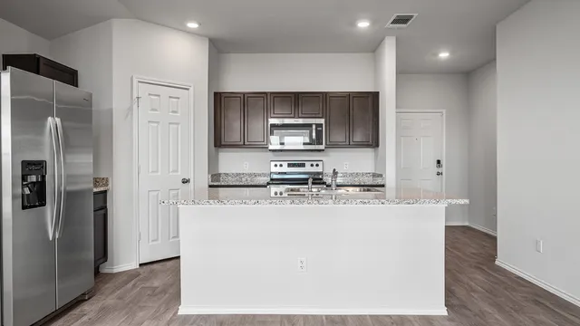 a kitchen with kitchen island stainless steel appliances a sink and a refrigerator