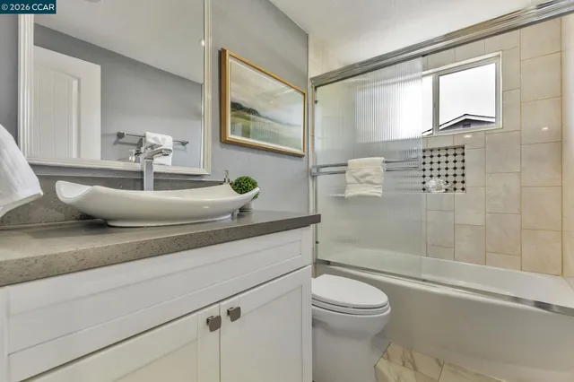 a bathroom with a granite countertop toilet sink and mirror