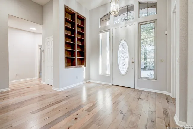 a view of an empty room with wooden floor and window