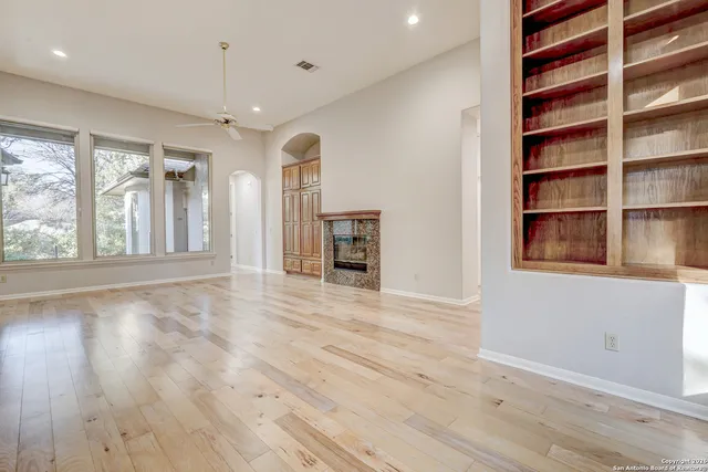 a view of an empty room with a window and wooden floor