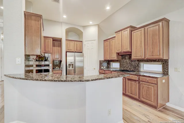 a kitchen with stainless steel appliances granite countertop a sink a stove and a refrigerator