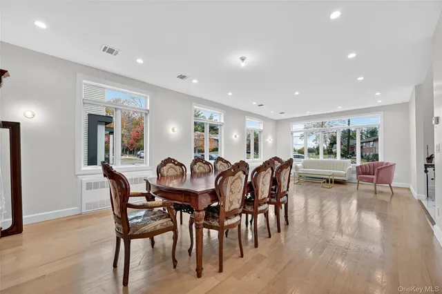 a view of dining room and livingroom with furniture wooden floor a rug a painting and a chandelier