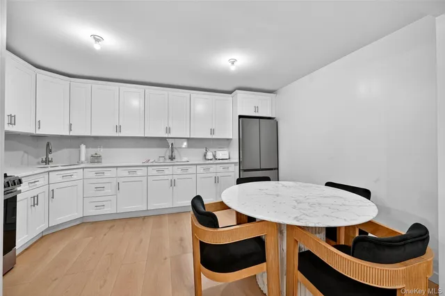 a kitchen with stainless steel appliances kitchen island a table chairs and a refrigerator