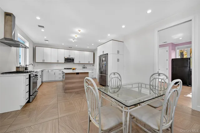 a kitchen with stainless steel appliances granite countertop a stove a refrigerator a kitchen island a table and chairs