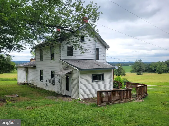 a green field with some trees in front of the house