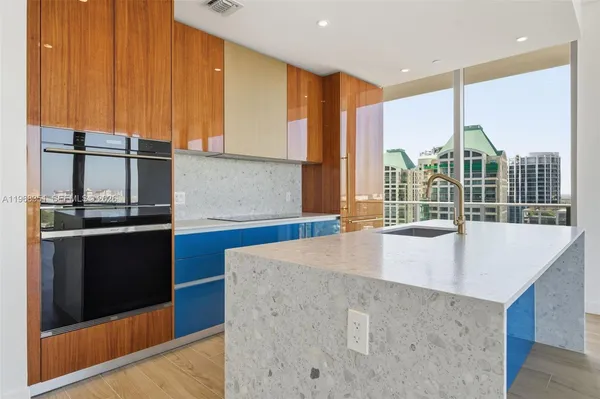 a view of kitchen with stainless steel appliances wooden floor and large window