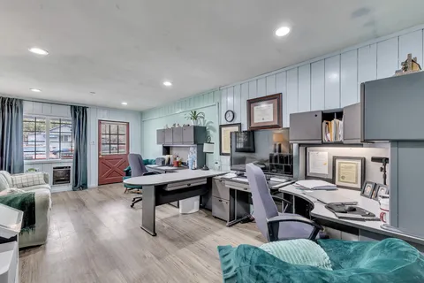 a kitchen with stainless steel appliances kitchen island granite countertop a refrigerator a stove top oven a dining table and chairs with wooden floor