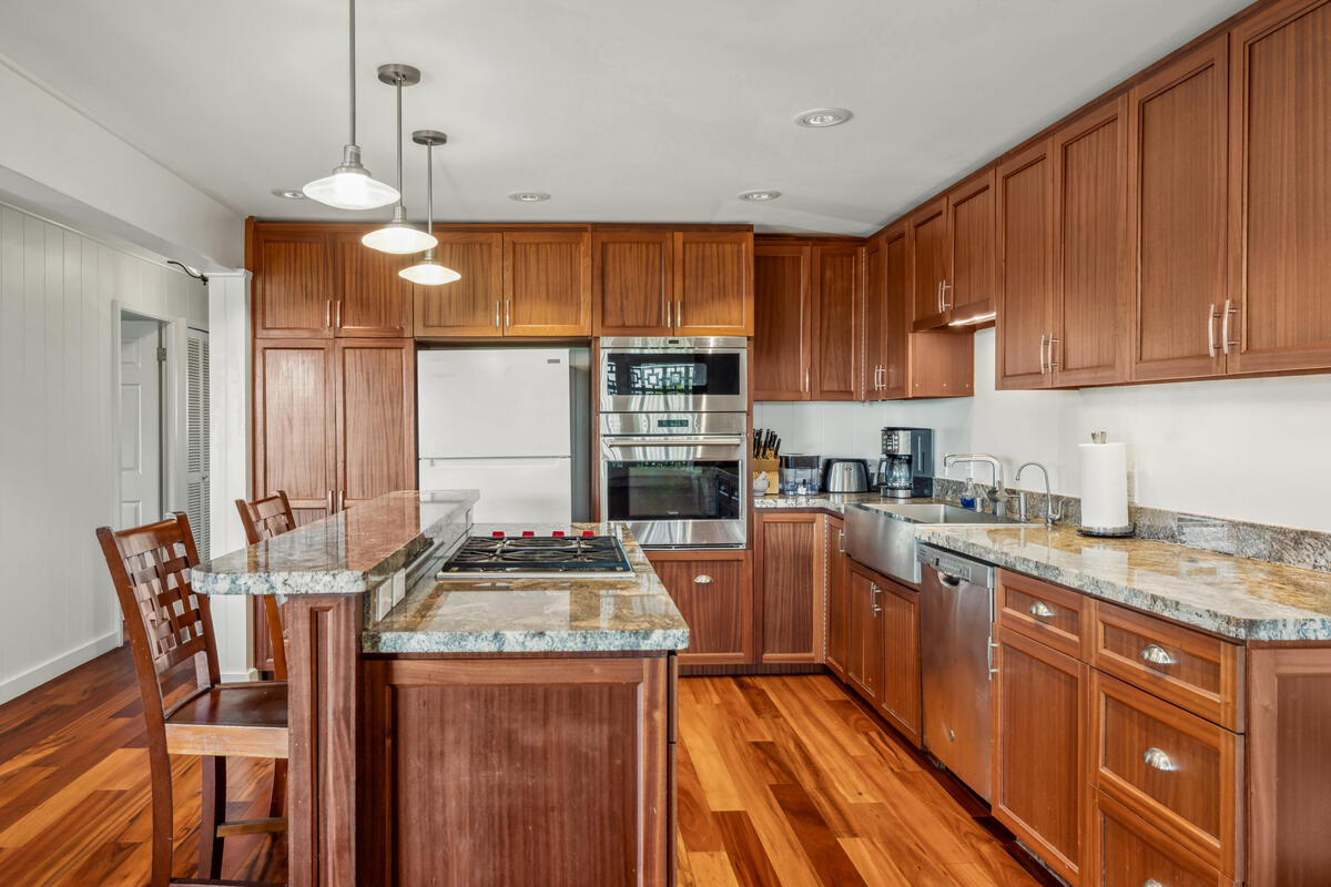 3567 Waha Road Kalaheo, HI 96741 - Photo 7 of 25 a kitchen with granite countertop wooden cabinets and a stove top oven
