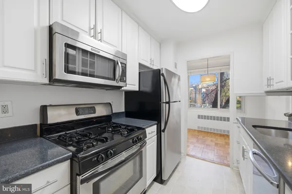 a kitchen with stainless steel appliances granite countertop a stove microwave refrigerator and sink