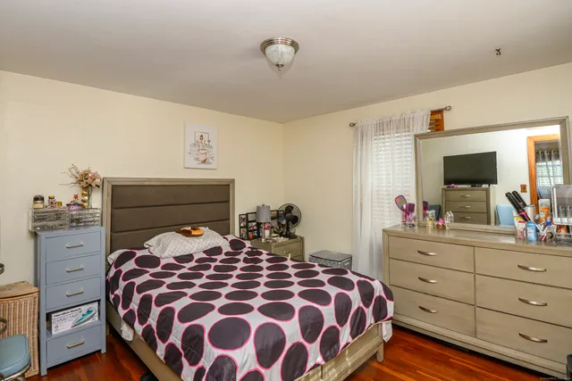 a bedroom with a large bed and a flat tv screen on dresser