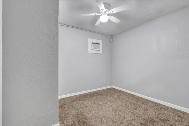 an empty room with a fan & a window