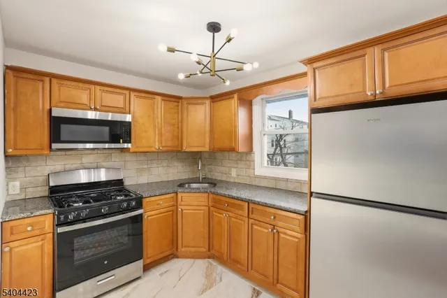 a kitchen with stainless steel appliances granite countertop a refrigerator a stove a sink and a microwave