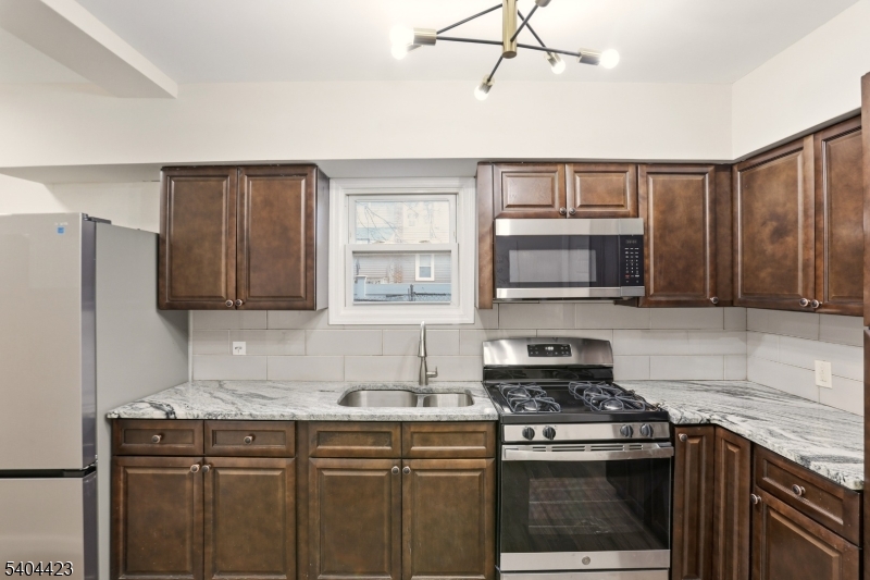 112 University Place Irvington, NJ 07111 - Photo 27 of 31 a kitchen with stainless steel appliances granite countertop a stove a sink and a refrigerator