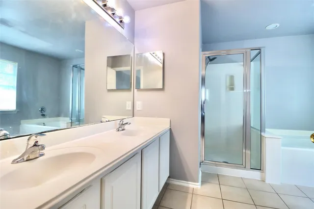 a bathroom with a double vanity sink mirror and bathtub