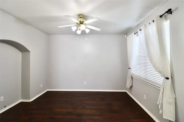a view of an empty room with wooden floor and fan