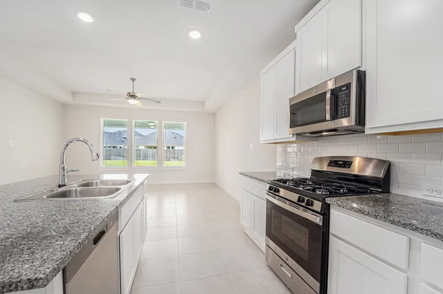 a kitchen with stainless steel appliances granite countertop a stove and a microwave