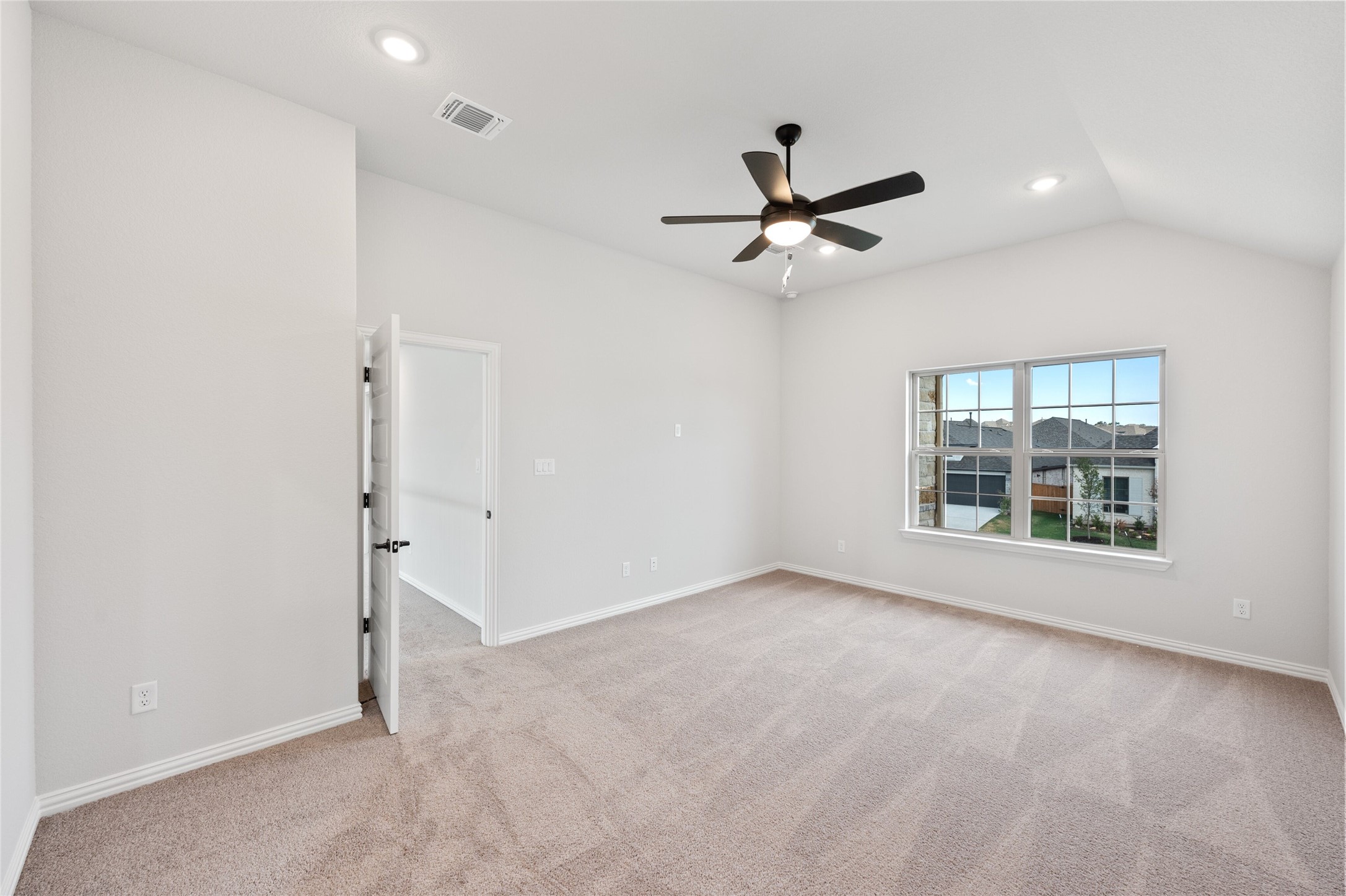 303 Fawn Riv Run Kyle, TX 78640 - Photo 15 of 32 Spacious room featuring vaulted ceilings, recessed lighting, a modern ceiling fan, large windows, and neutral carpeting