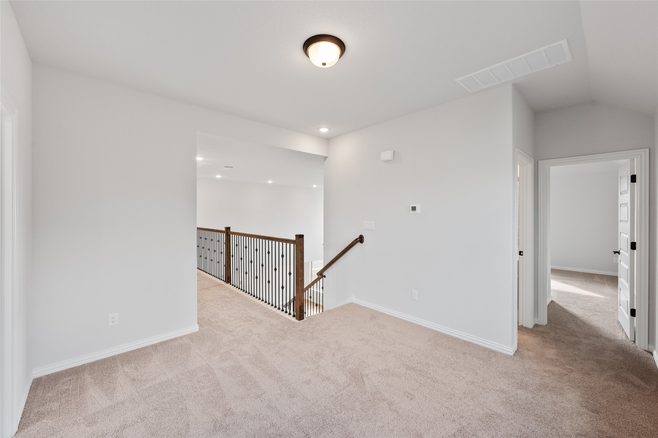 303 Fawn Riv Run Kyle, TX 78640 - Photo 21 of 32 Carpeted landing with a wood and wrought iron staircase railing
