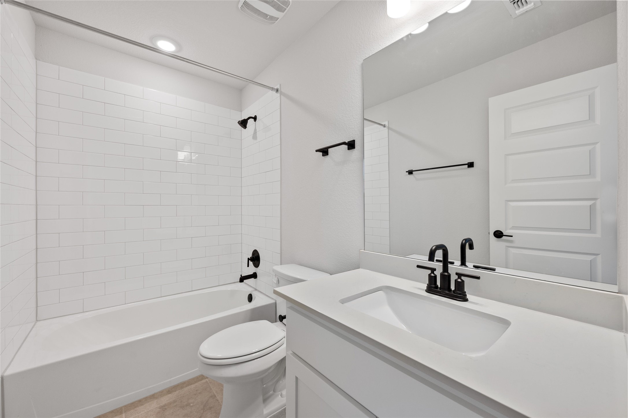 303 Fawn Riv Run Kyle, TX 78640 - Photo 23 of 32 Bathroom featuring a white subway tile shower surround, a built-in bathtub, and matte black plumbing fixtures