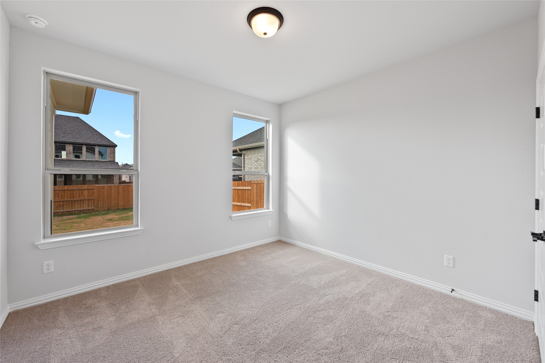 303 Fawn Riv Run Kyle, TX 78640 - Photo 26 of 32 Light-filled interior space featuring two large windows, neutral wall paint, and plush carpeting
