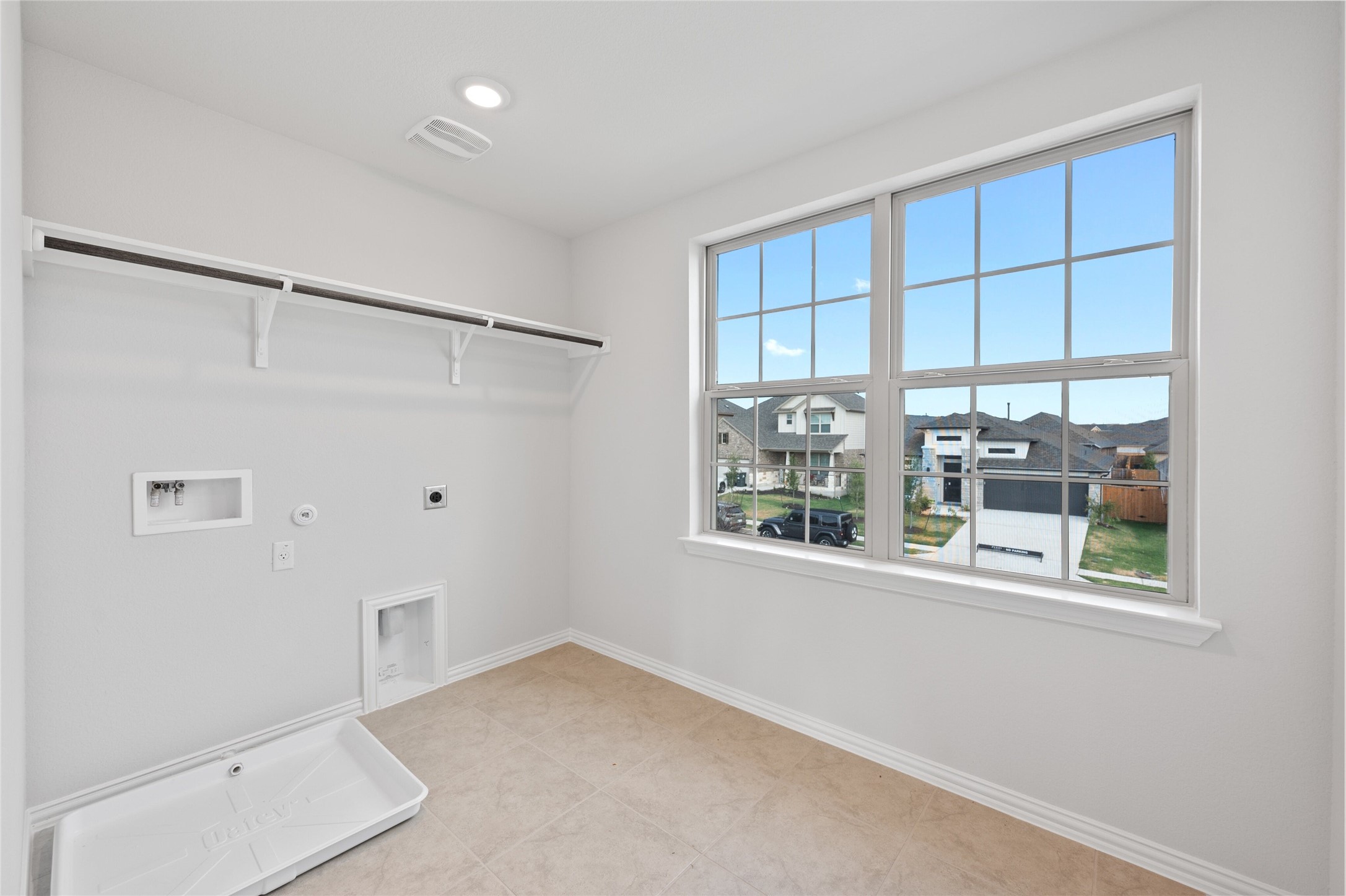 303 Fawn Riv Run Kyle, TX 78640 - Photo 28 of 32 Laundry room featuring a large window, tile flooring, recessed lighting, and a built-in shelf with a hanging rod