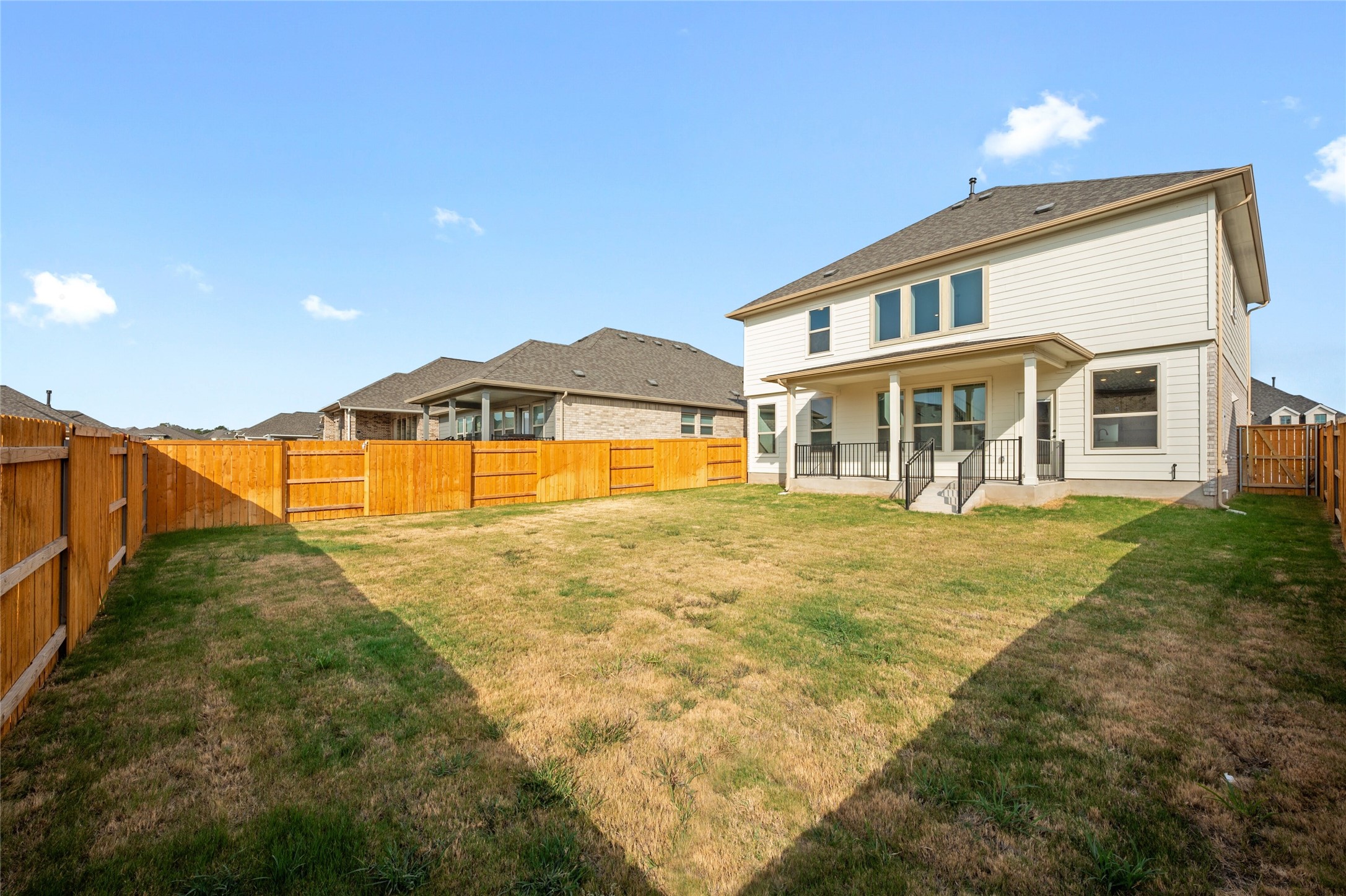 303 Fawn Riv Run Kyle, TX 78640 - Photo 30 of 32 Expansive backyard with wood fencing and a covered patio featuring white columns and black railings