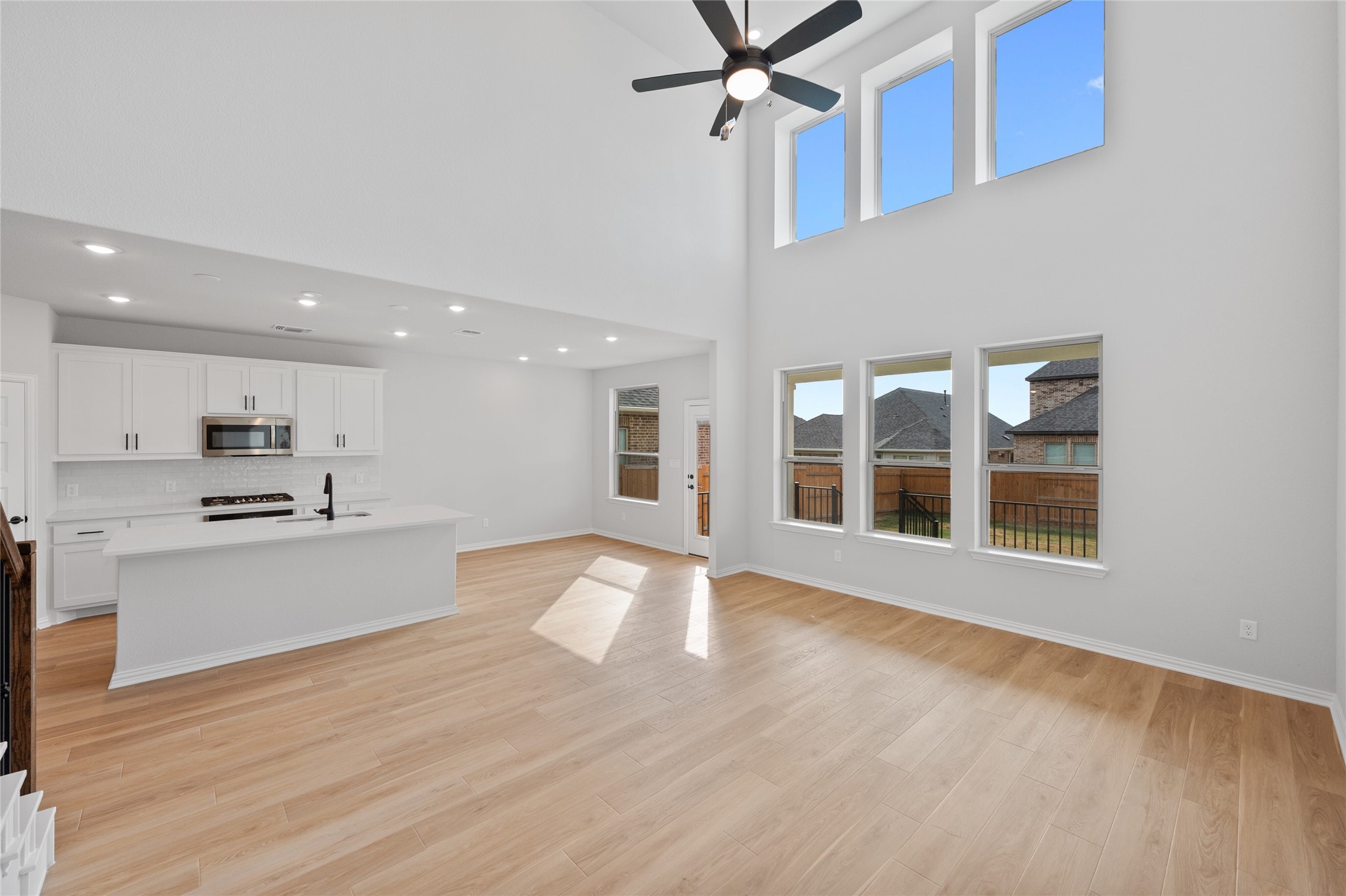 303 Fawn Riv Run Kyle, TX 78640 - Photo 4 of 32 Open-concept living space featuring high ceilings, wood-finish flooring, a contemporary ceiling fan, and multiple windows providing ample natural light