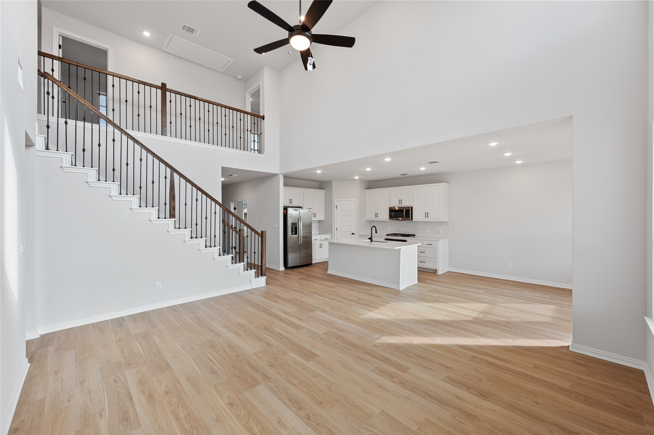 303 Fawn Riv Run Kyle, TX 78640 - Photo 5 of 32 Open-concept living space featuring wood-finish flooring, a two-story ceiling, and recessed lighting
