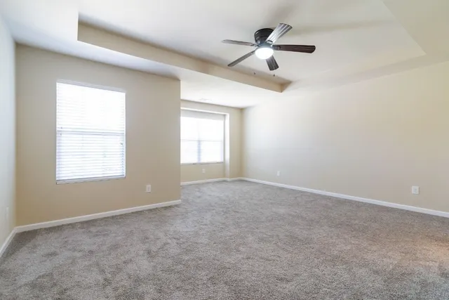 an empty room with windows and ceiling fan