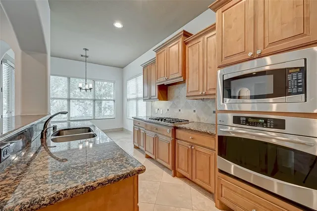 a kitchen with stainless steel appliances granite countertop a stove a sink and a microwave