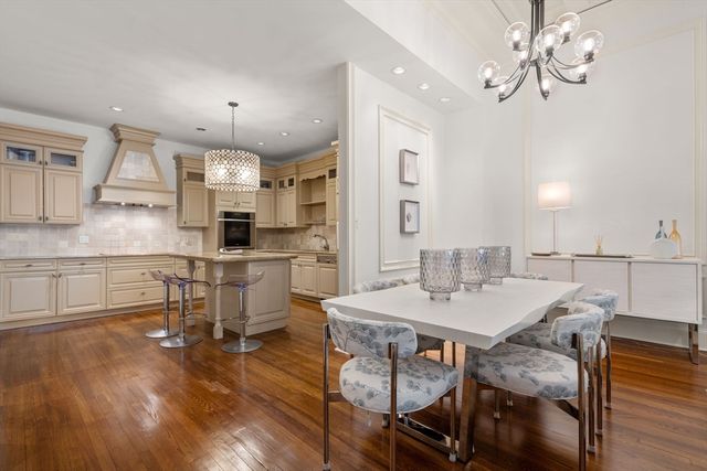 a kitchen with kitchen island a dining table chairs stainless steel appliances and cabinets