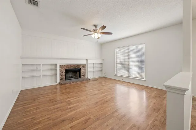 a view of an empty room with a fireplace and a window