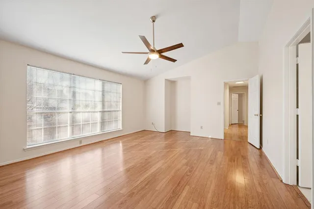a view of empty room with wooden floor and fan