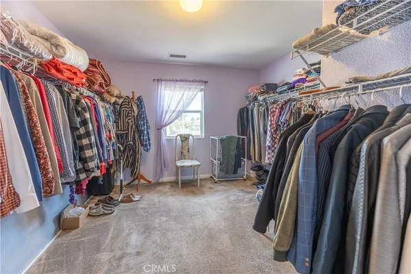 a view of walk in closet with clothes and shoes