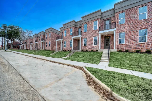 a view of a brick building next to a yard with big trees