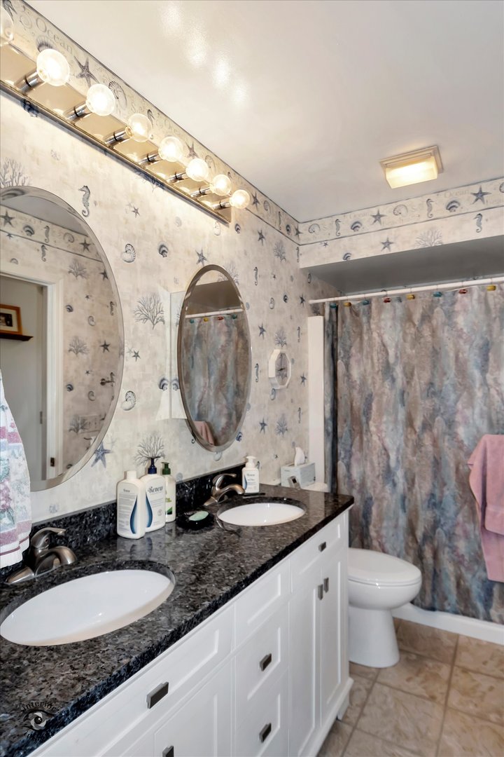 605 Ridge Street Wilmington, IL 60481 - Photo 23 of 26 a bathroom with a granite countertop toilet sink and mirror