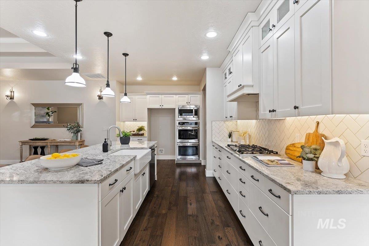 1366 North Waterbrook Way Star, ID 83669 - Photo 13 of 30 Kitchen featuring white cabinets, light stone counters, a center island with sink, and dark wood-style floors