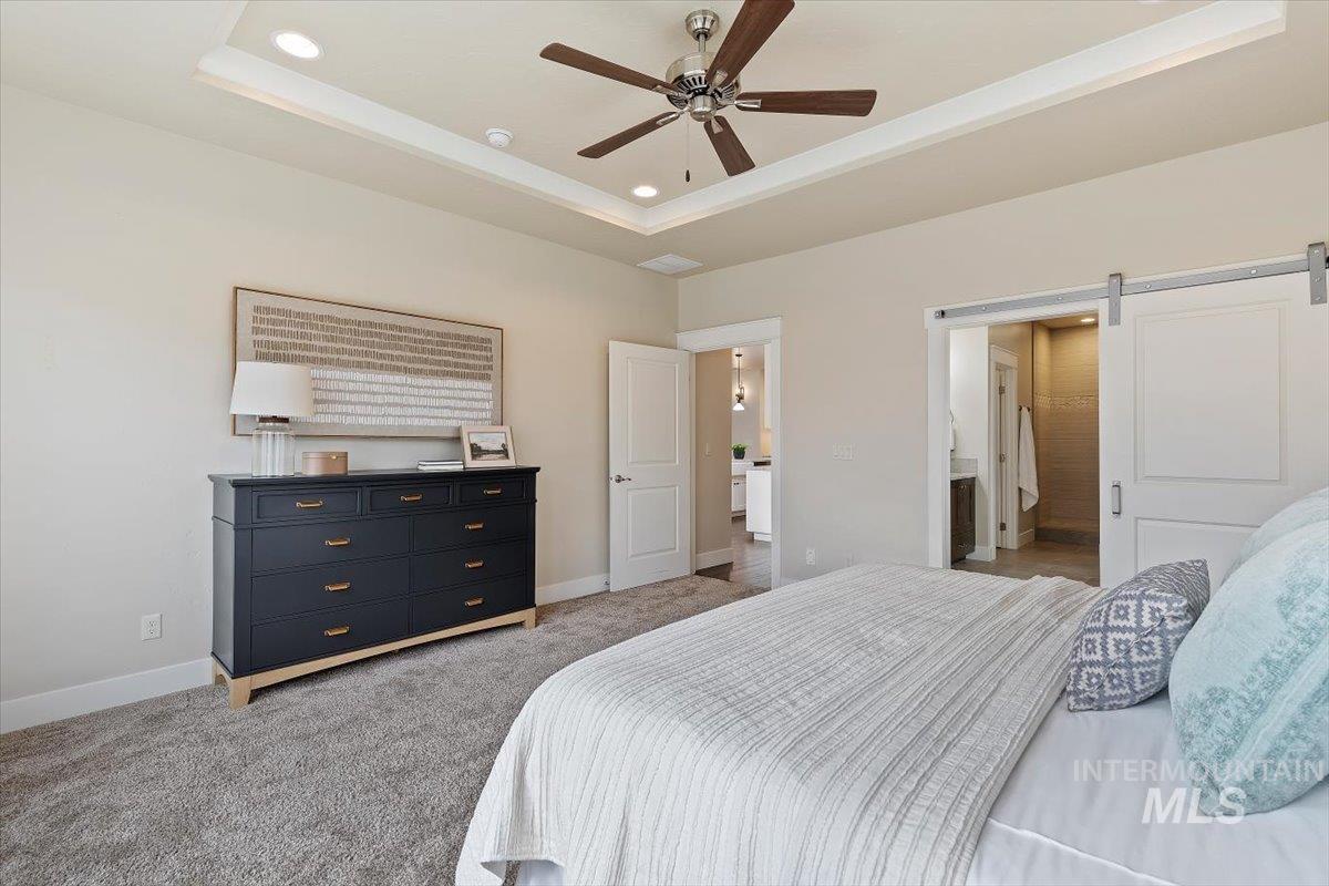 1366 North Waterbrook Way Star, ID 83669 - Photo 15 of 30 Bedroom with a barn door, carpet flooring, a tray ceiling, a ceiling fan, and recessed lighting