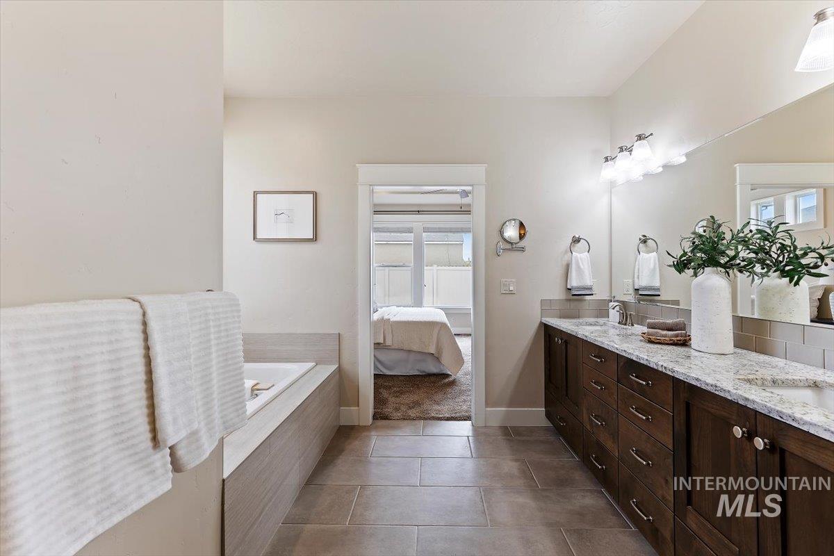 1366 North Waterbrook Way Star, ID 83669 - Photo 17 of 30 Ensuite bathroom featuring double vanity, a garden tub, dark tile patterned flooring, and tasteful backsplash