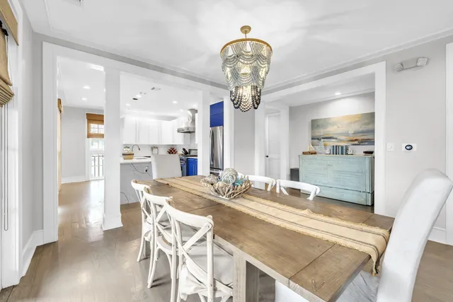 a view of a dining room and livingroom with furniture wooden floor a rug a painting and a chandelier