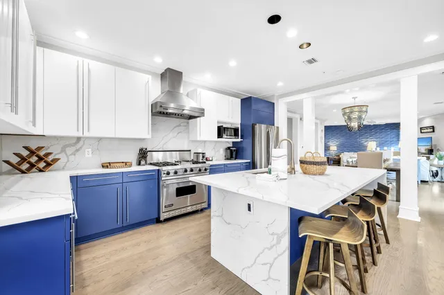 a kitchen with stainless steel appliances a refrigerator a stove a sink dishwasher and a refrigerator with wooden floor