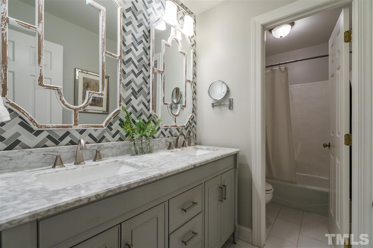 772 Weathergreen Drive Raleigh, NC 27615 - Photo 1 of 26 This bathroom has dual vanities and a tub with white tile and gorgeous gray tile flooring.