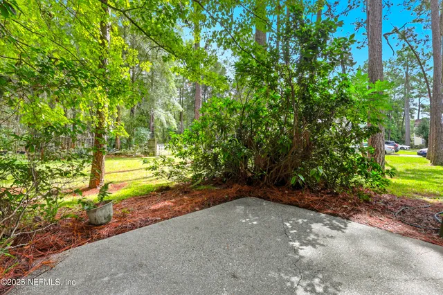 a view of a white house with a big yard and large tree
