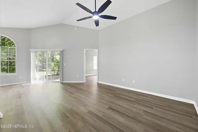 an empty room with wooden floor and ceiling fan