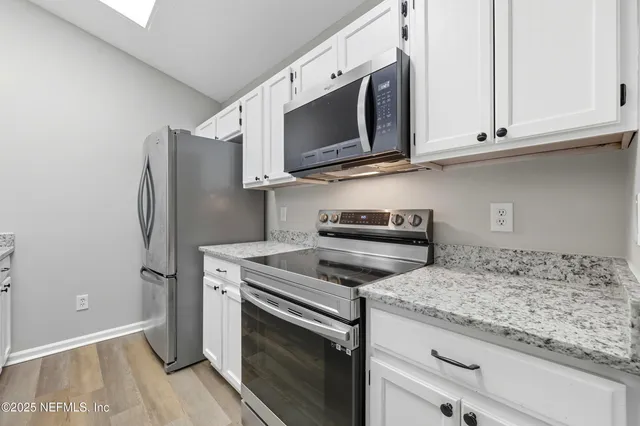 a kitchen with granite countertop white cabinets and a sink