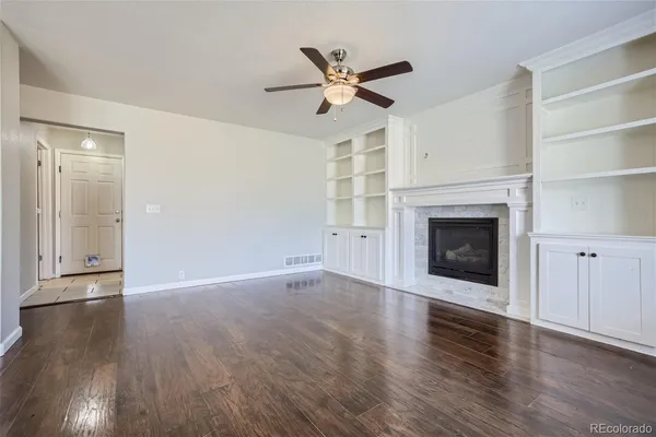 a view of an empty room with wooden floor and a fireplace